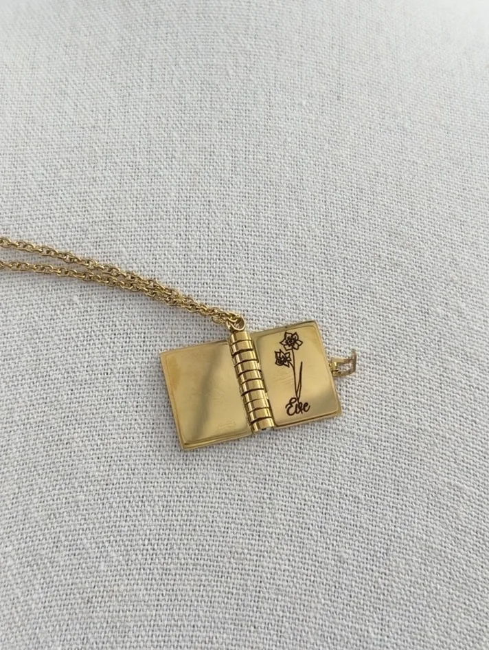 Personalized gold book necklace engraved with flowers and the name Eloe