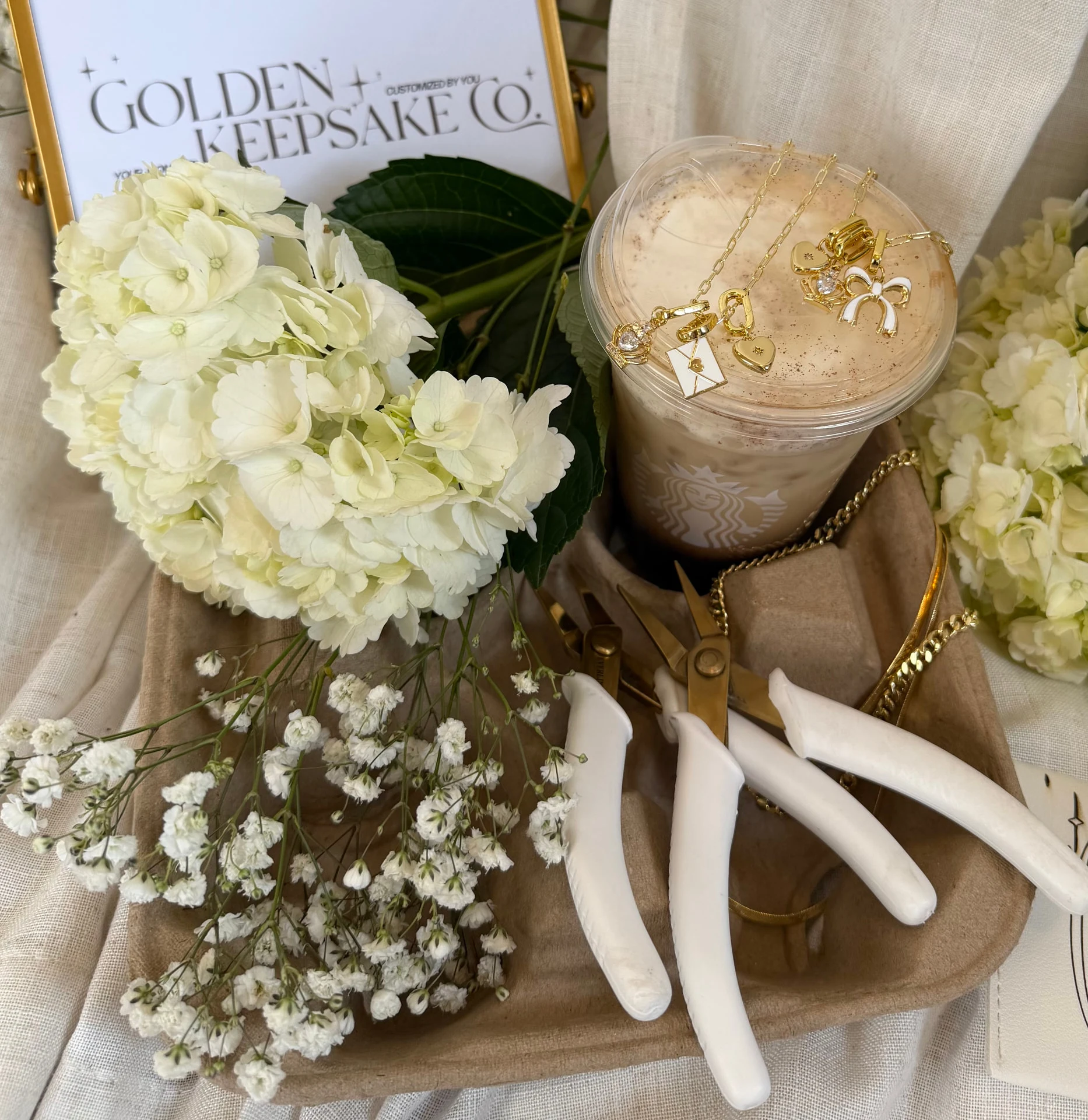 Golden Keepsake Co. jewelry displayed with coffee and white flowers