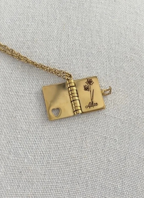 Personalized gold book necklace engraved with flowers and the name Alice